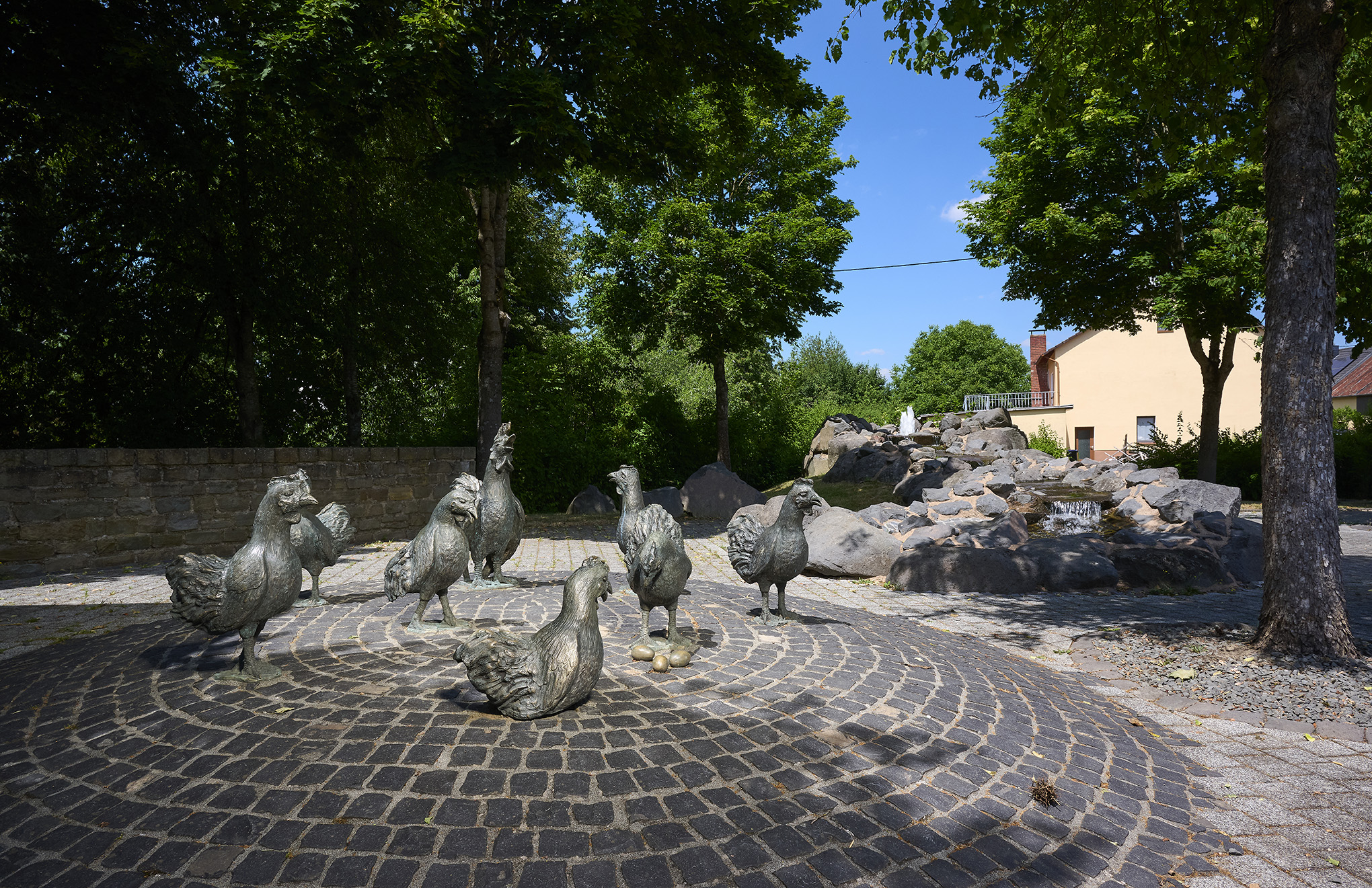 Hühnerbrunnen mit Bronzefiguren im Ortskern von Strohn in der Vulkaneifel