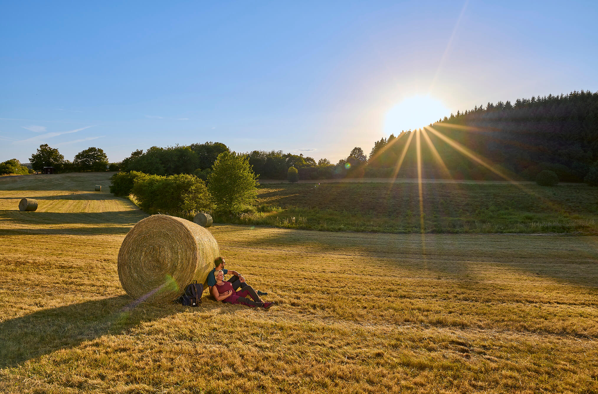 Wanderer bei einer Rast in der sommerlichen Landschaft rund um Strohn in der Vulkaneifel