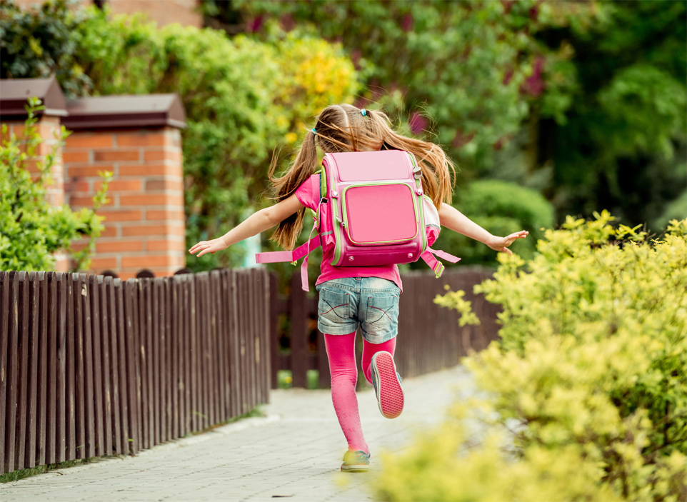 Schulkind mit pinkem Schulranzen auf dem Weg zur Schule in Strohn