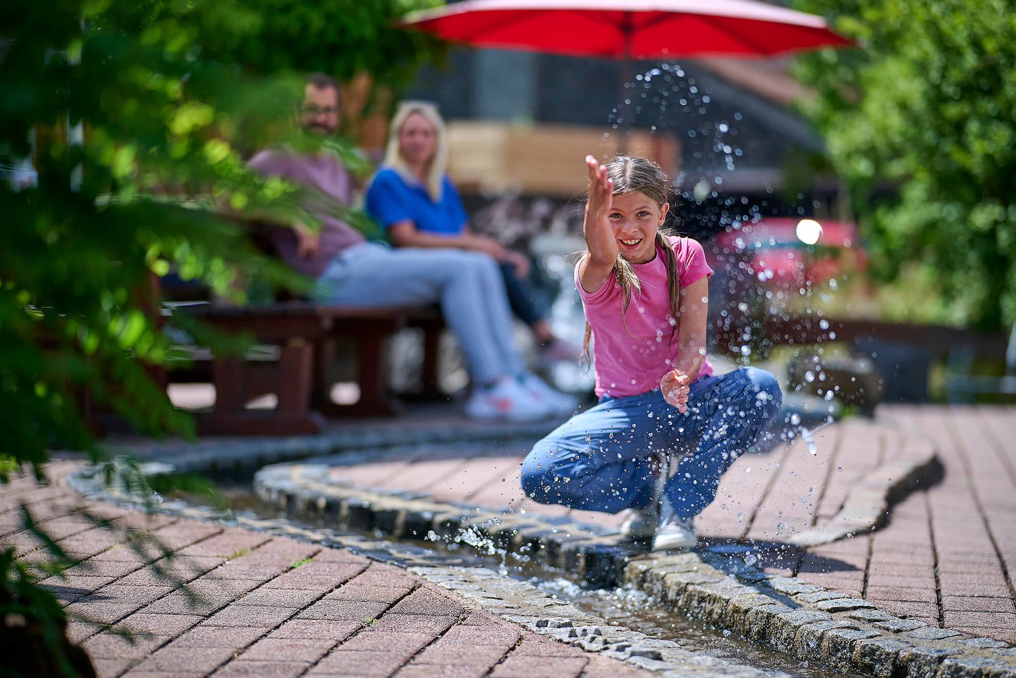 Kind spielt mit einem Wasserlauf im Außenbereich des Vulkanhauses Strohn